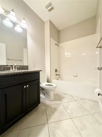 a spacious bathroom with a granite countertop sink a toilet and a mirror