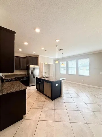 a large kitchen with a counter top space a sink stainless steel appliances and cabinets