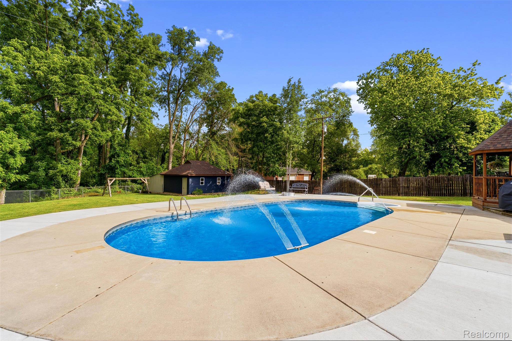 6699 Lansing Road Durand, MI 48429 - Photo 40 of 53 Oval-shaped inground pool featuring integrated water features and a concrete surround