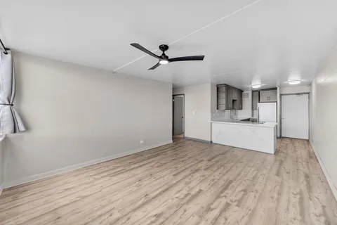 a view of empty room with wooden floor and ceiling fan