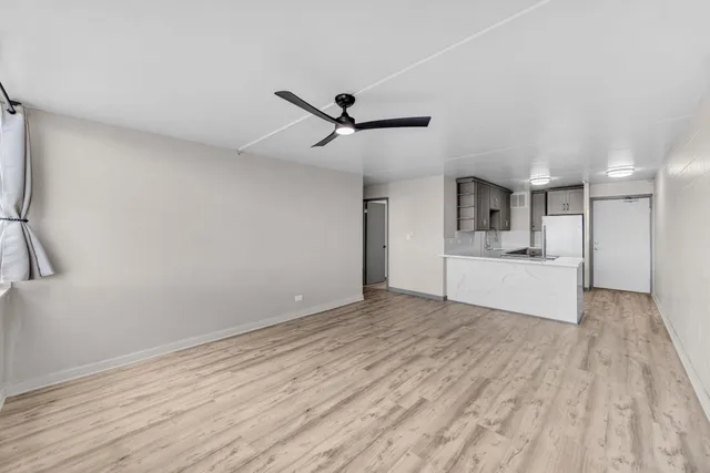 a view of empty room with wooden floor and ceiling fan