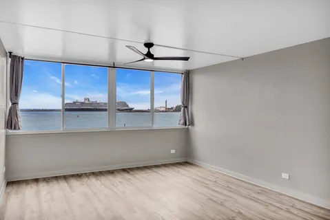 a view of an empty room with a window and wooden floor