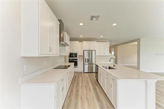 a kitchen with white cabinets sink and stainless steel appliances