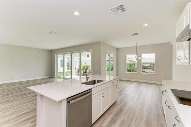 a large white kitchen with a window wooden floor and stainless steel appliances