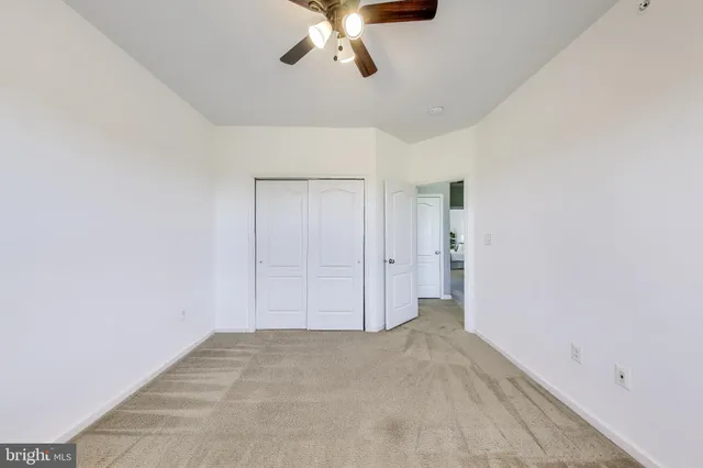 a view of an empty room and chandelier fan