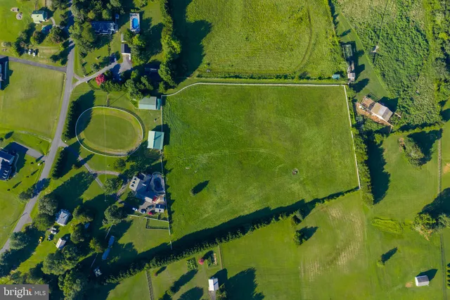 an aerial view of a residential houses with outdoor space and trees all around