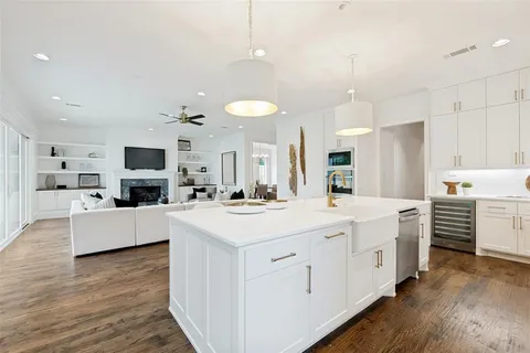 a large white kitchen with kitchen island a white cabinets and wooden floor