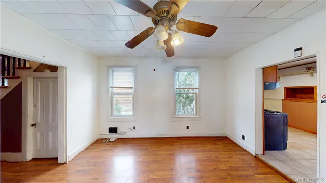 a view of an empty room with window and wooden floor