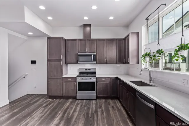 a kitchen with stainless steel appliances granite countertop a refrigerator a stove top oven a sink and dishwasher