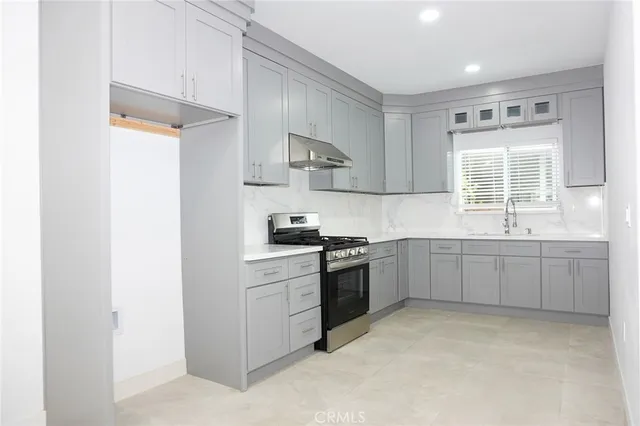 a kitchen with a sink stove top oven and cabinets