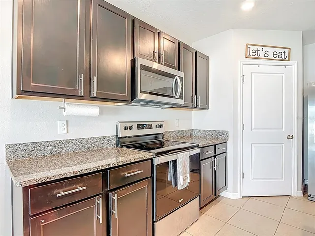 a kitchen with stainless steel appliances granite countertop a stove top oven a sink a dining table and chairs