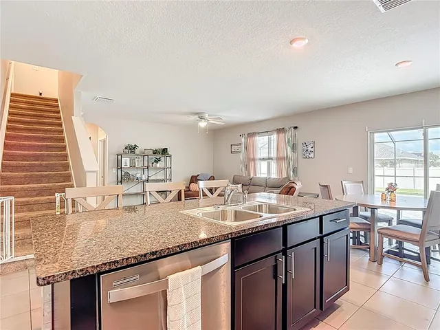 a kitchen with stainless steel appliances granite countertop a stove top oven a sink a dining table and chairs