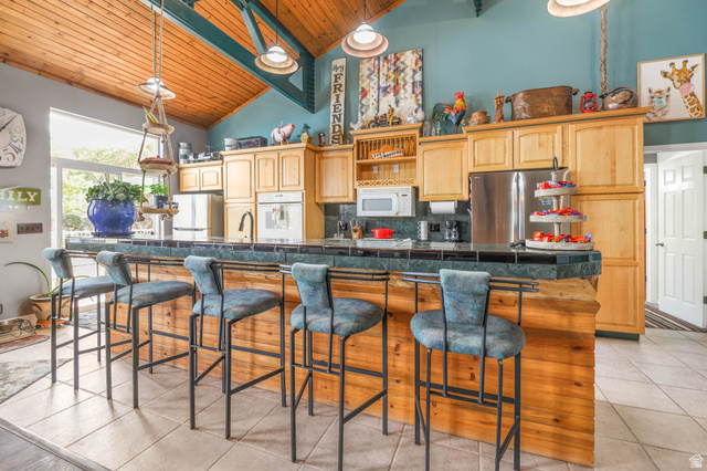 569 Elk Meadow Loop Tooele, UT 84074 - Photo 19 of 56 Kitchen featuring a kitchen breakfast bar, a large island, white appliances, light tile patterned floors, and a vaulted wooden ceiling