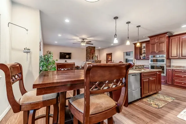 a kitchen with stainless steel appliances granite countertop a stove top oven a refrigerator a sink dishwasher a dining table and chairs with wooden floor