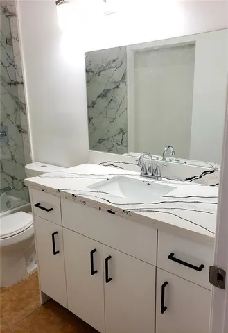 a bathroom with a granite countertop sink a toilet and bathtub