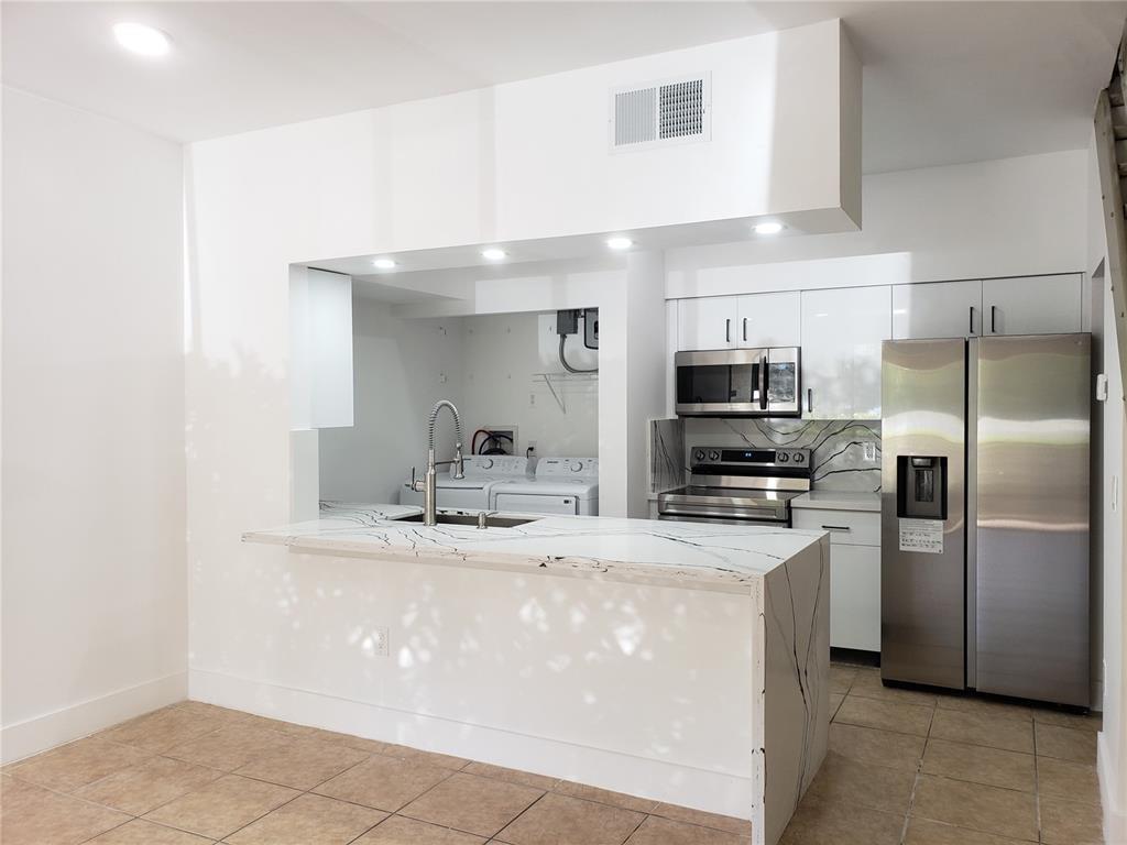 18338 Northwest 68th Avenue, Unit B Hialeah, FL 33015 - Photo 4 of 21 a kitchen with stainless steel appliances a sink stove refrigerator and cabinets