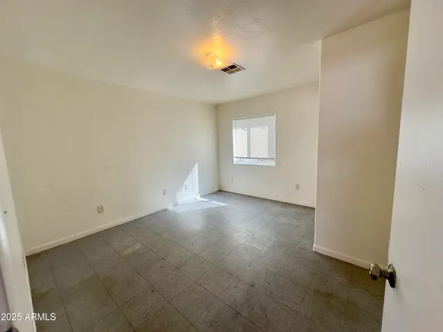 an empty room with a window and chandelier fan