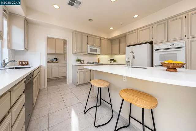 a kitchen with stainless steel appliances a refrigerator sink and white cabinets