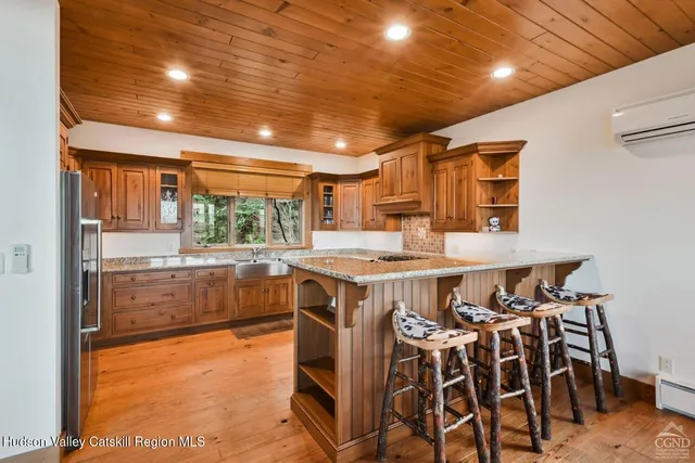 a kitchen with stainless steel appliances granite countertop a refrigerator a sink dishwasher a dining table and chairs with wooden floor