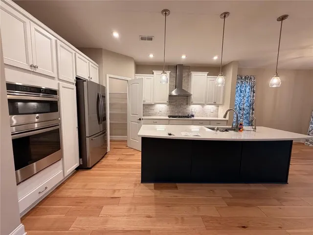 a view of kitchen with kitchen island stainless steel appliances a sink cabinets and wooden floor
