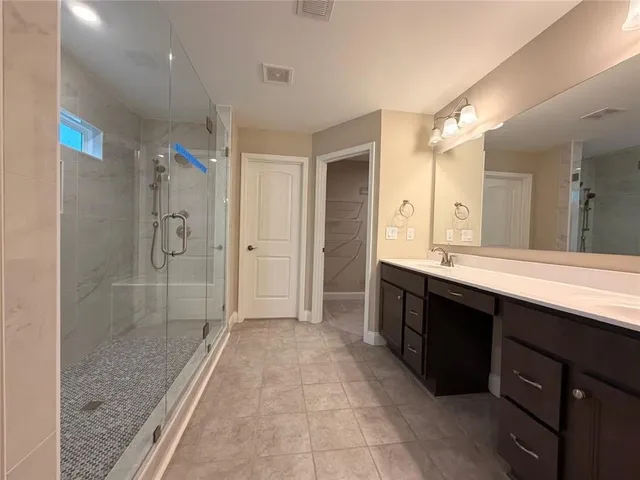 a spacious bathroom with a shower sink and mirror