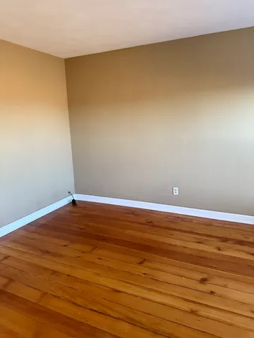 an empty room with wooden floor and a window