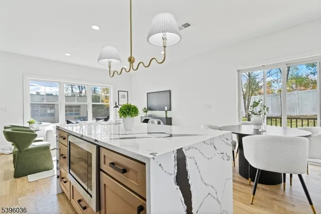 a dining hall with stainless steel appliances granite countertop a kitchen island a stove and a wooden cabinets