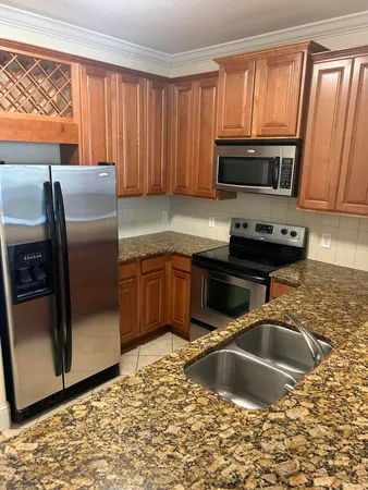 a kitchen with stainless steel appliances granite countertop a sink a stove and a refrigerator with wooden cabinets