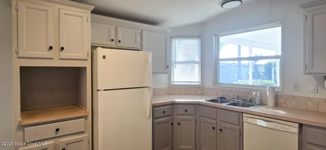 a white refrigerator freezer sitting in a kitchen with white cabinets