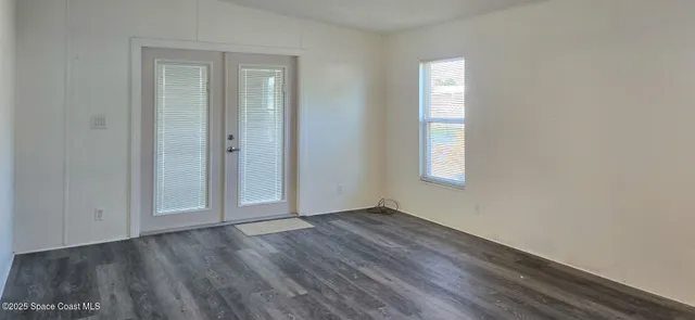 an empty room with wooden floor and window