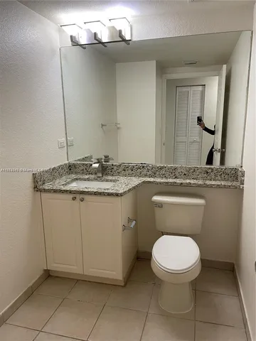 a bathroom with a granite countertop toilet and a sink