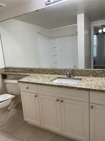 a bathroom with a granite countertop sink and a toilet