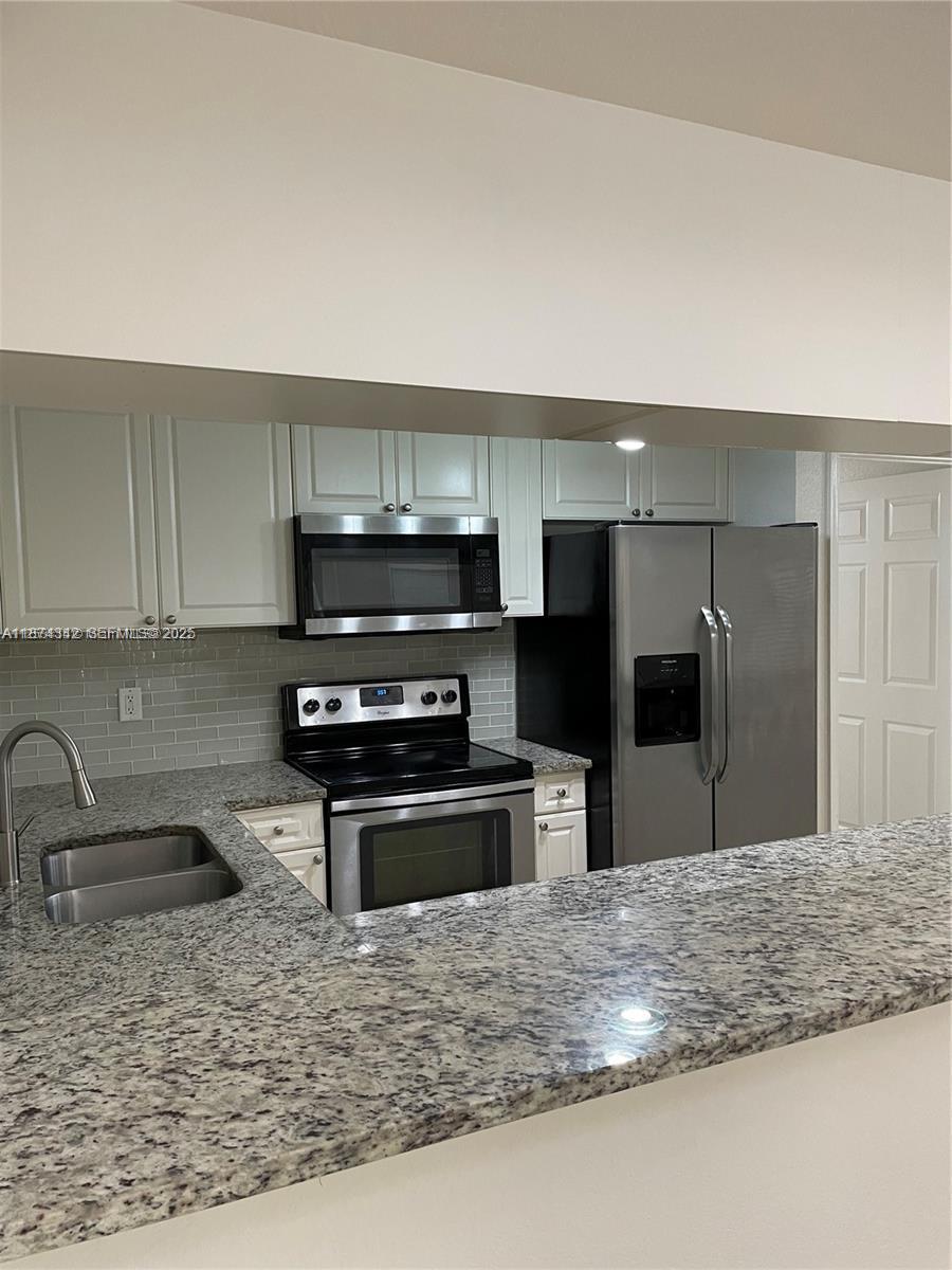 6312 West Sample Road, Unit 6312 Coral Springs, FL 33067 - Photo 9 of 21 a kitchen with stainless steel appliances granite countertop a sink and a stove