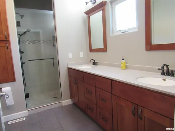 a bathroom with a double vanity sink mirror and shower