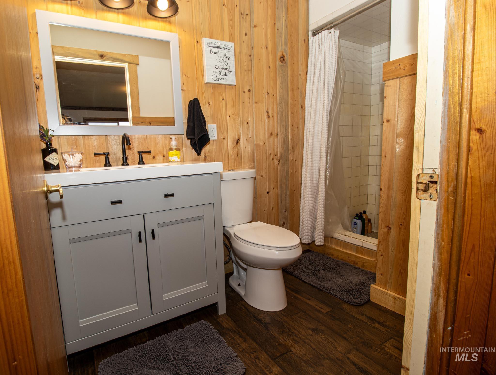 272 Cemetery Road Weippe, ID 83553 - Photo 26 of 43 Full bath with wood walls, a stall shower, vanity, and dark wood-style flooring
