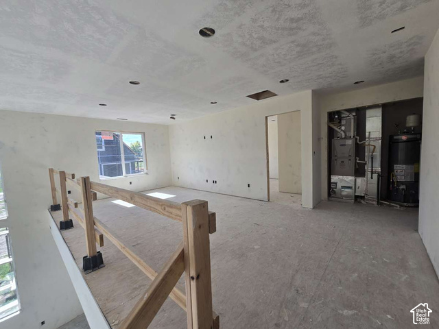 338 West 3400 South Logan, UT 84321 - Photo 24 of 40 Open-concept interior featuring unfinished drywall, a large window, a partial wooden railing, and exposed utilities