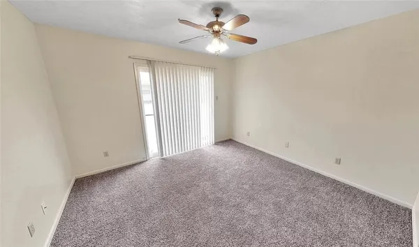 an empty room with a chandelier fan and windows