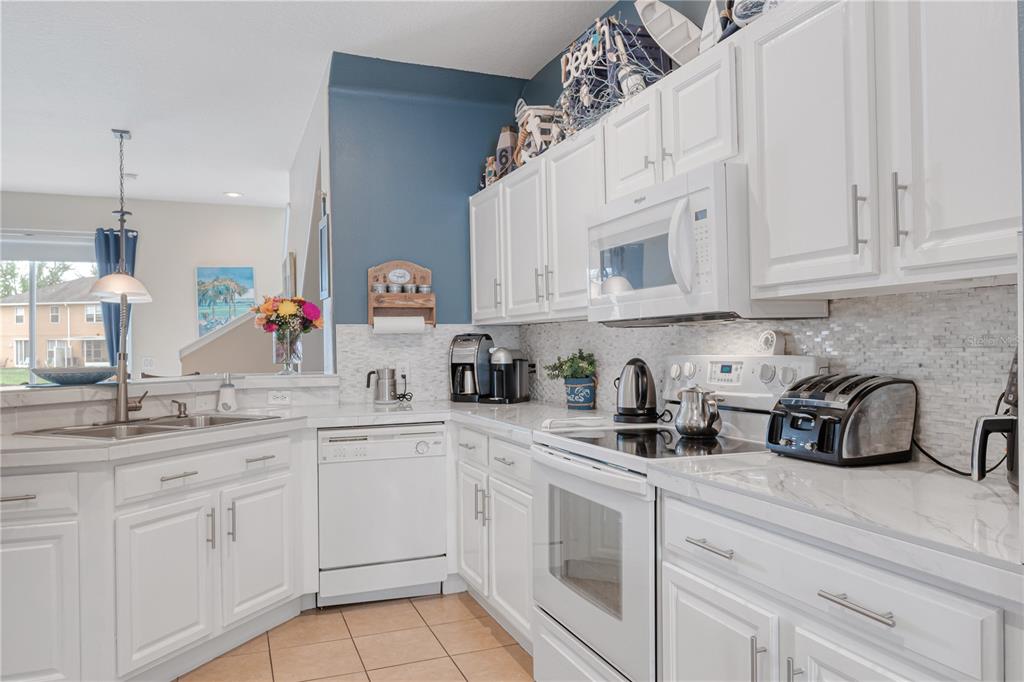 4925 Poolside Drive St. Cloud, FL 34769 - Photo 5 of 36 a kitchen with white cabinets and white appliances