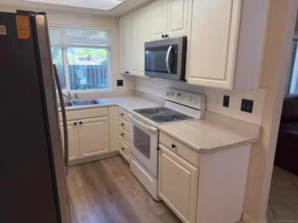 a kitchen with white cabinets sink and appliances