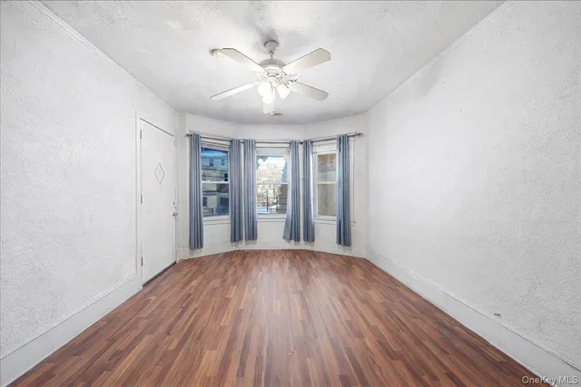 an empty room with chandelier fan and windows