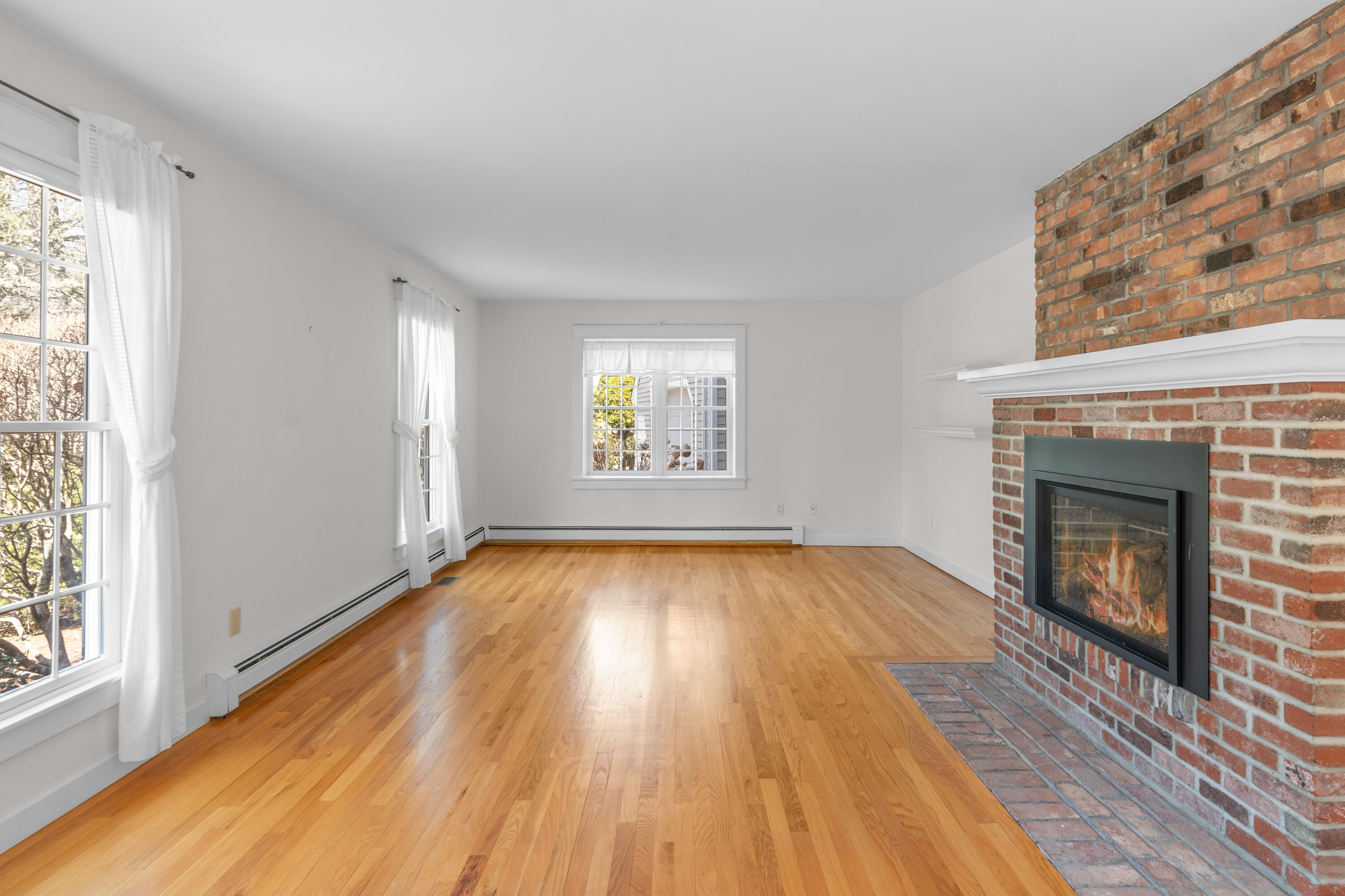 51 Walton Heath Way Mashpee, MA 02649 - Photo 11 of 35 an empty room with wooden floor fireplace and windows