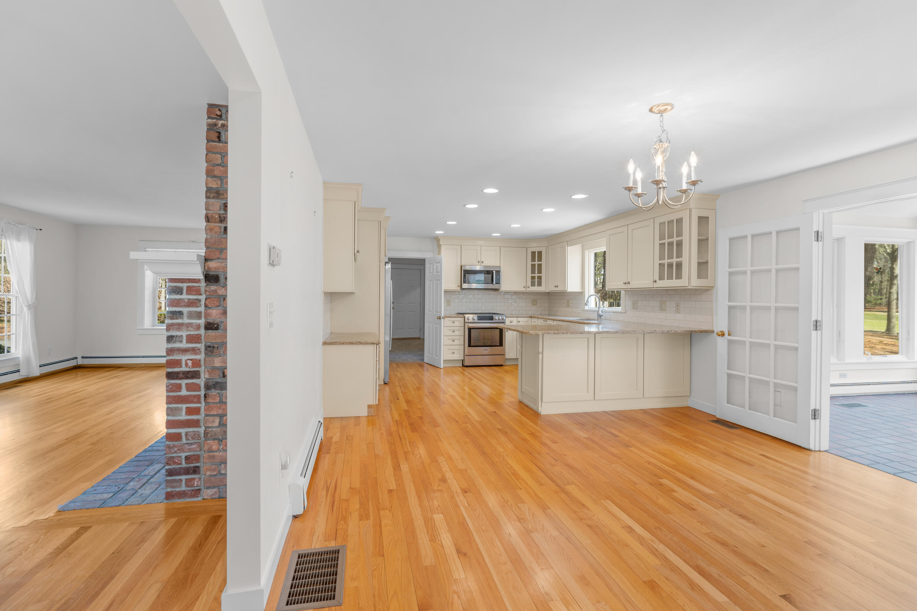51 Walton Heath Way Mashpee, MA 02649 - Photo 7 of 35 a large white kitchen with kitchen island a stove a refrigerator a sink dishwasher with a dining table and chairs with wooden floor