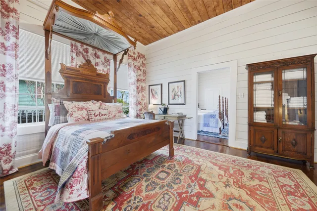 a bedroom with a bed wooden floor and large window