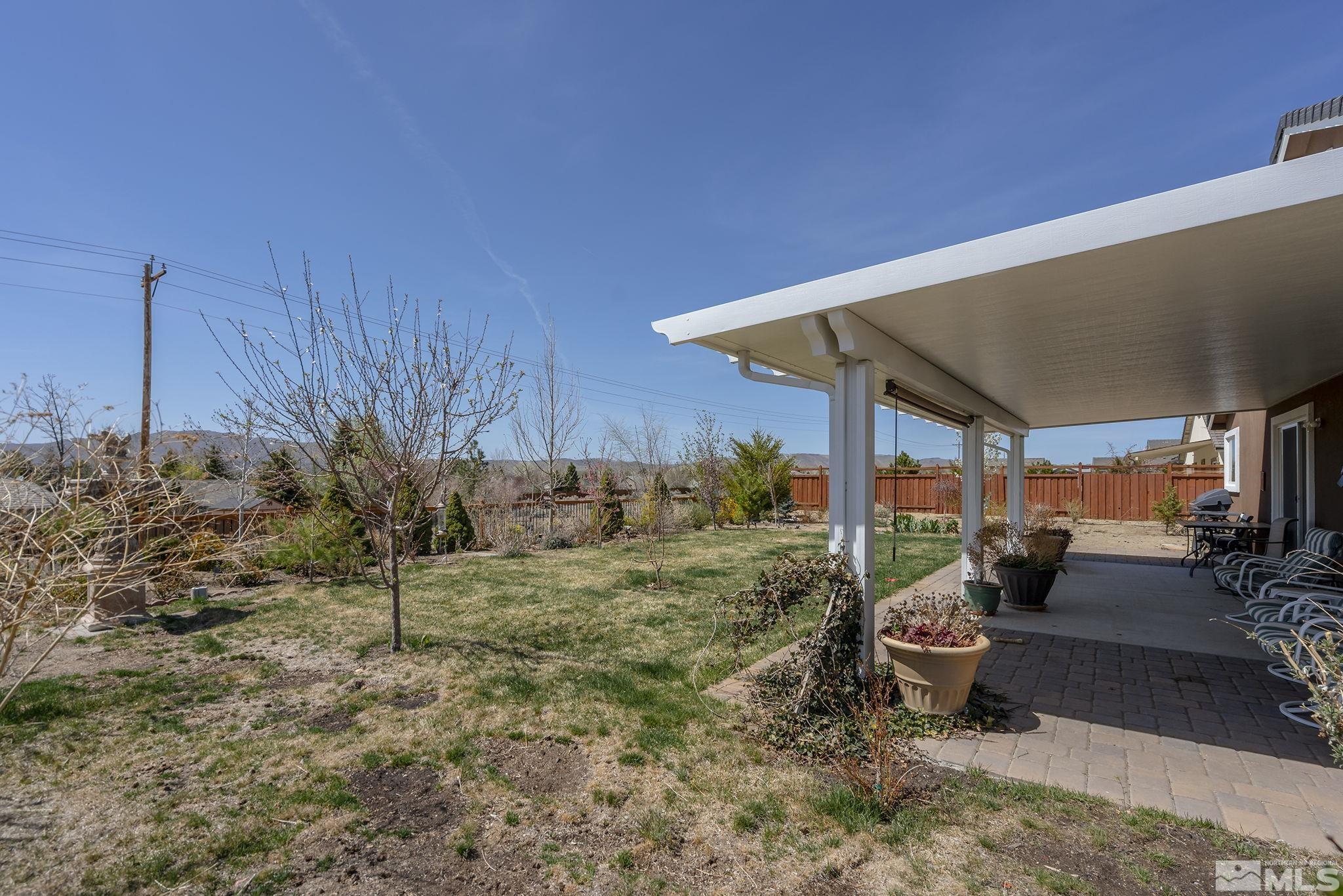 7707 Rhythm Circle Sparks, NV 89436 - Photo 21 of 25 a view of a patio with table and chairs under an umbrella with wooden fence
