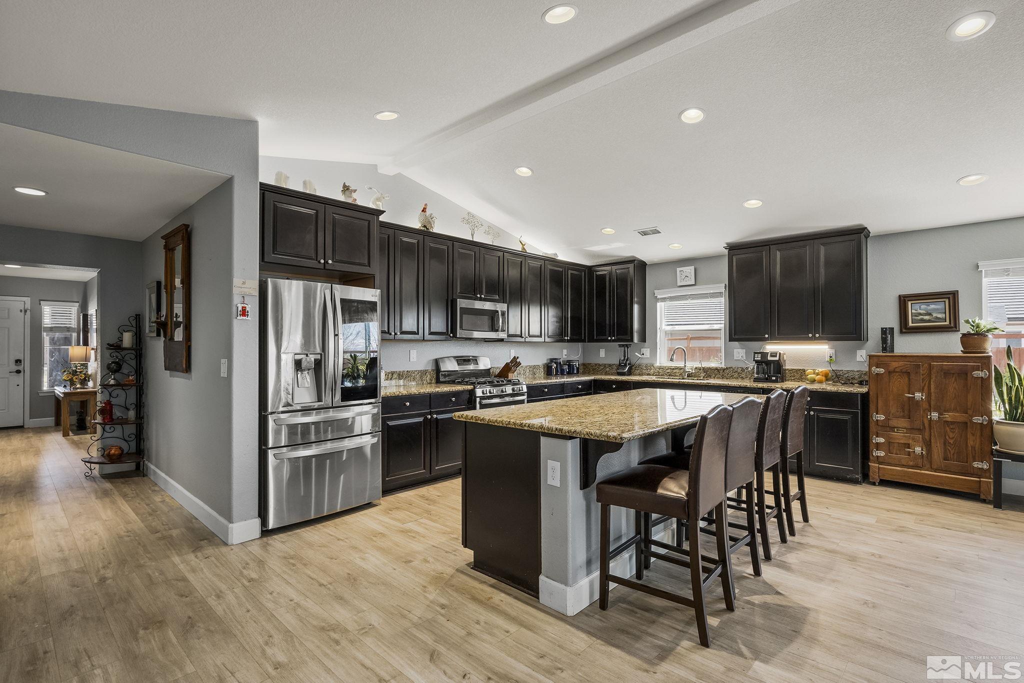 7707 Rhythm Circle Sparks, NV 89436 - Photo 9 of 25 a kitchen with stainless steel appliances granite countertop a table chairs sink refrigerator and microwave