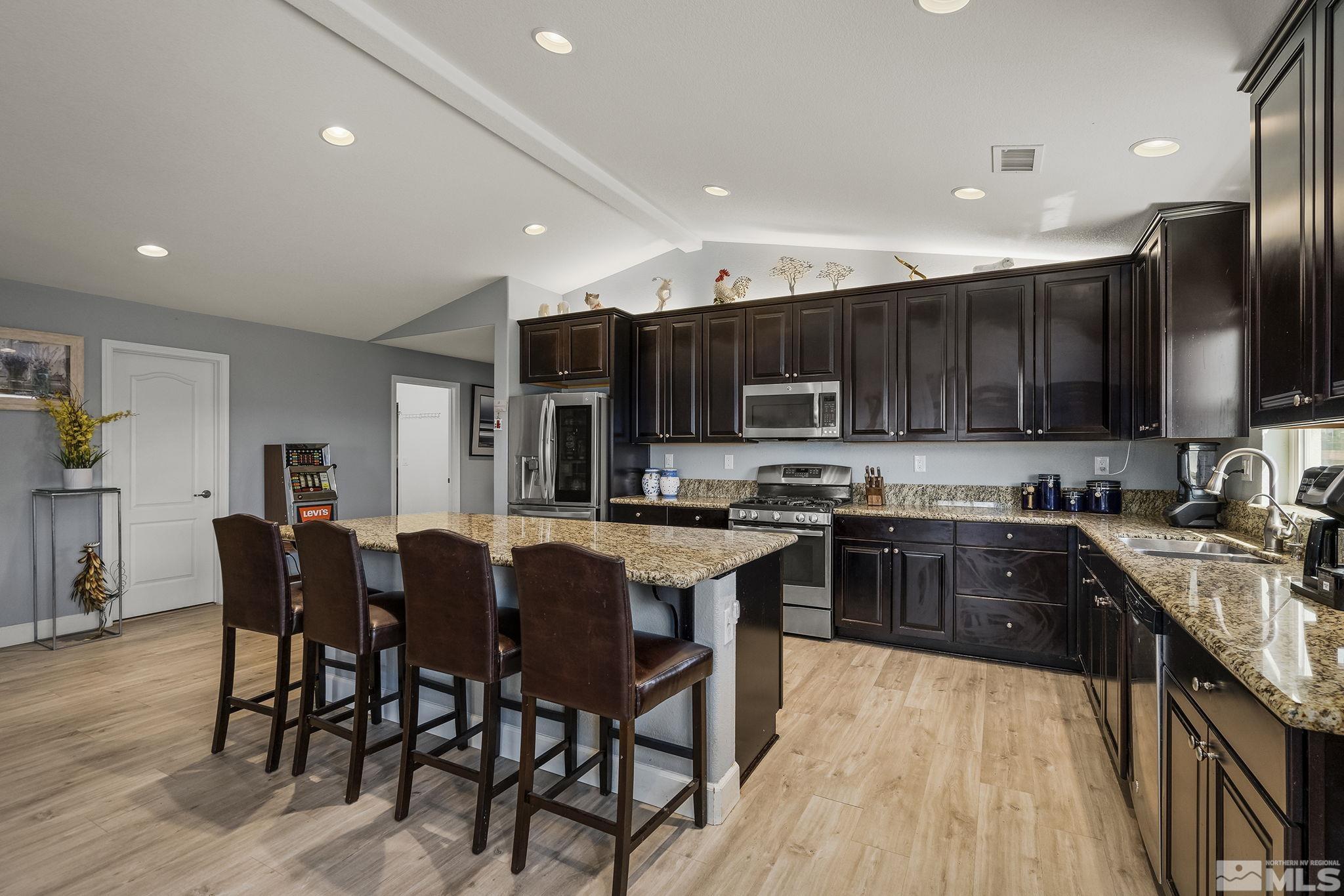 7707 Rhythm Circle Sparks, NV 89436 - Photo 10 of 25 a kitchen with stainless steel appliances granite countertop a stove top oven a sink a refrigerator and white cabinets with wooden floor