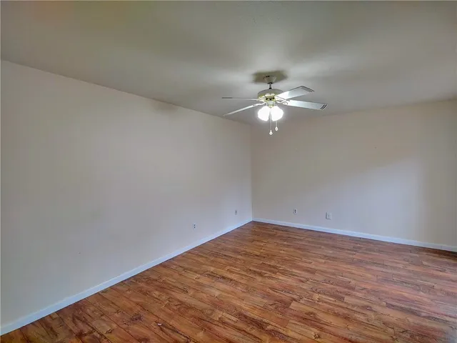 a view of a room with wooden floor and a chandelier fan