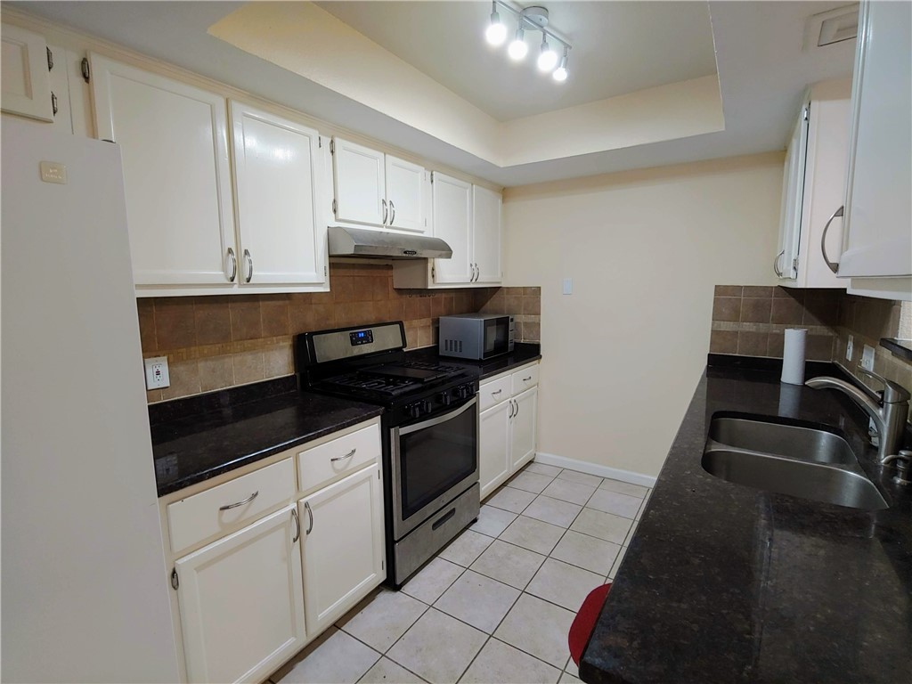 8340 Fathom Circle, Unit 401D Austin, TX 78750 - Photo 6 of 16 a kitchen with granite countertop a stove and a sink