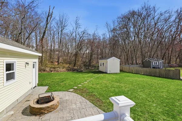 a view of a backyard with table and chairs potted plants and large tree
