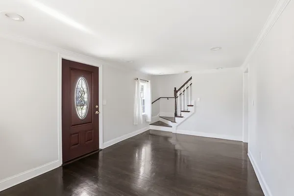 an empty room with wooden floor cabinet and windows